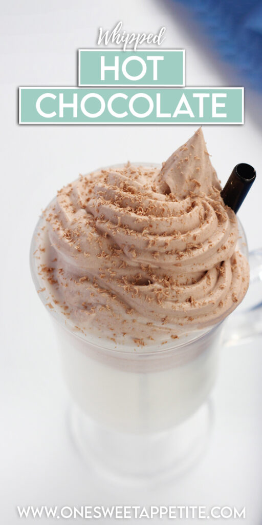 close up image showing a glass mug filled with chocolate whipped topping and chocolate shavings on a white table with a blue napkin. Text overlay reads "whipped hot chocolate"