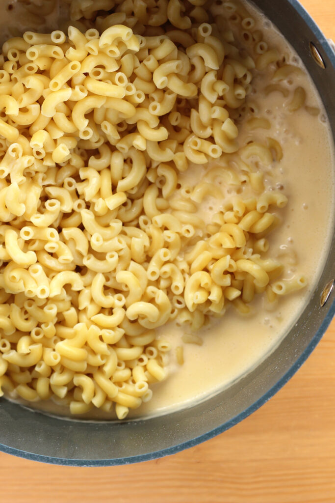 close up showing a large pot filled with cheese sauce and macaroni noodles