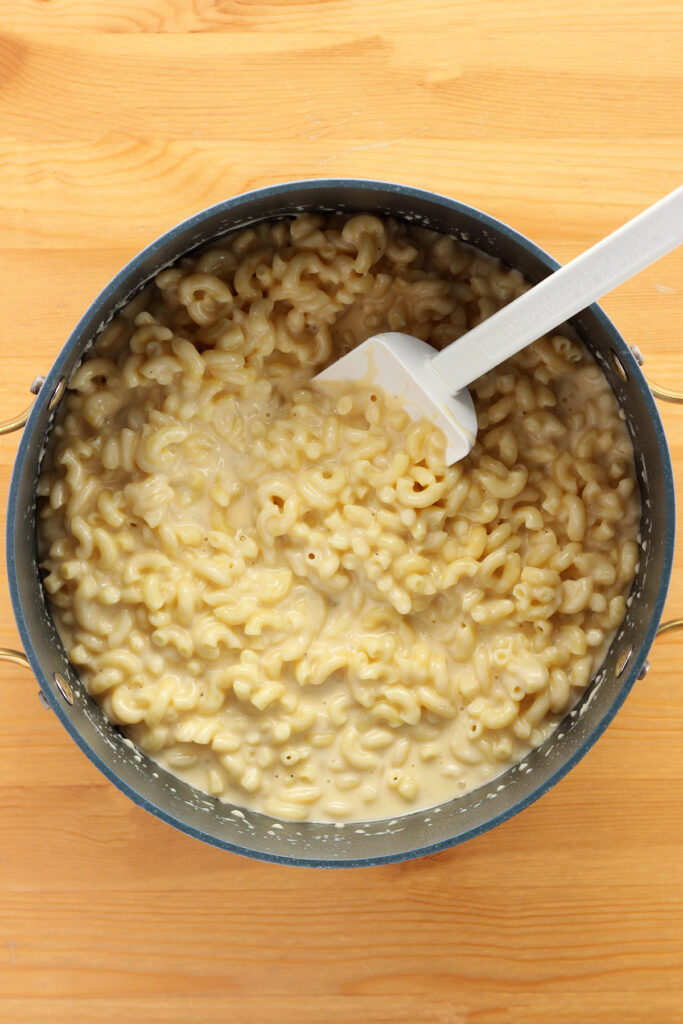  a large pot filled with cheese sauce and macaroni noodles