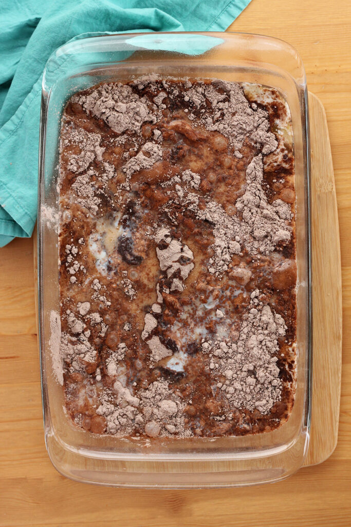 top down image of a 9x13 pan filled with cake mix that has been swirled with butter and milk but not fully mixed