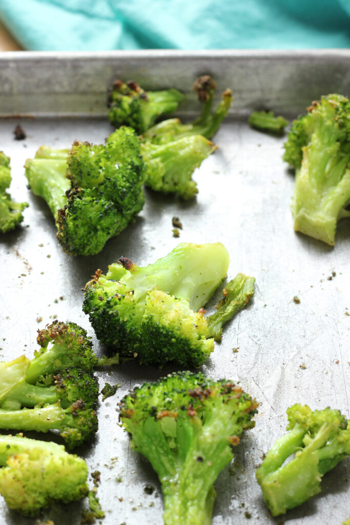 close up of a silver pan covered in roasted broccoli