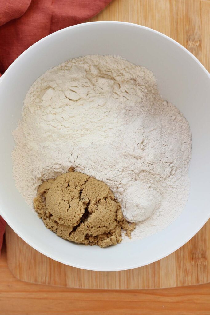 top down image showing a white mixing bowl filled with cake mix, flour, and brown sugar