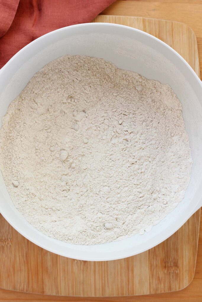 top down image showing a white mixing bowl filled with cake mix, flour, and brown sugar that has been mixed together