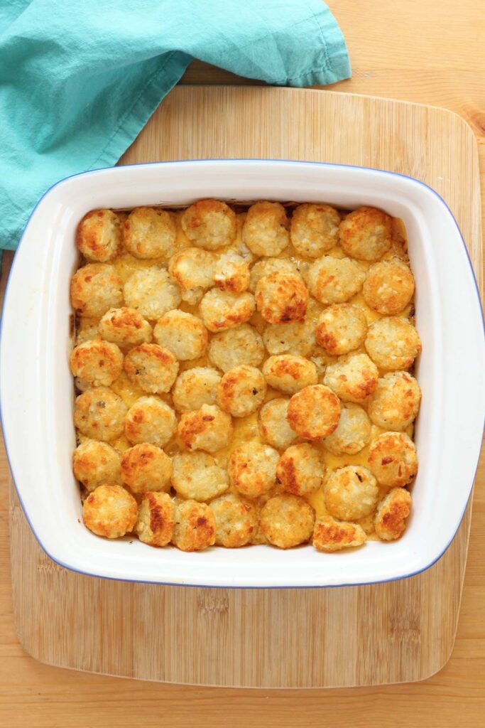 Top down image showing a casserole topped with tater tots in a white baking dish