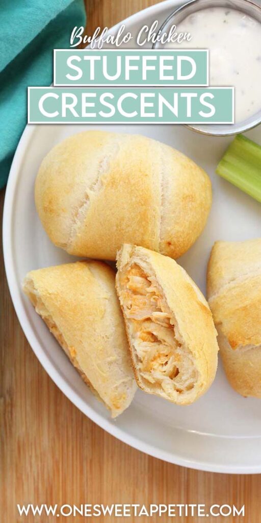 close up image showing three crescent pockets, one cut in half and filled with chicken and cheese, sitting on a white round plate with three celery sticks and a small dish of ranch dressing. The plate is sitting on a wooden table top with a teal napkin off in the back. Text overlay reads "buffalo chicken stuffed crescents"