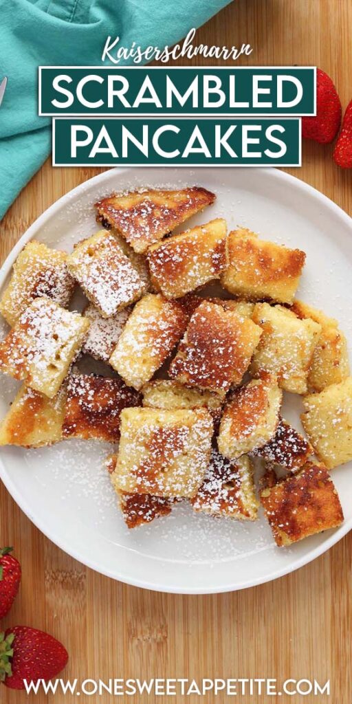 top down image showing a white round plate with square pieces of caramelized pancakes that have been dusted in powdered sugar. The plate is sitting on a wooden table with strawberries and a teal napkin around the sides. Text overlay reads "scrambled pancakes"