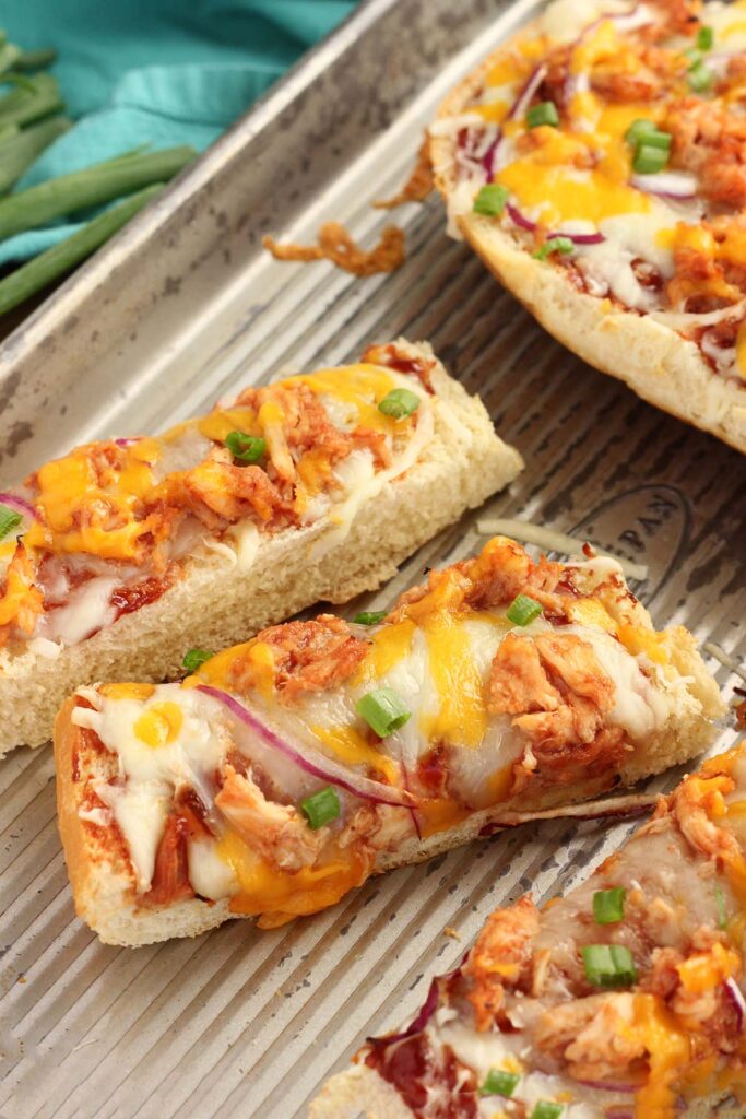 close up showing slices of french bread pizza with chicken and onion on a baking tray