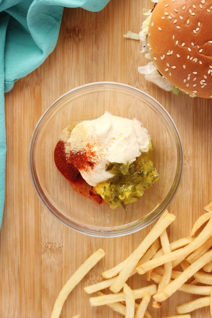Top down image showing a glass bowl with mayo, relish, mustard, and seasoning