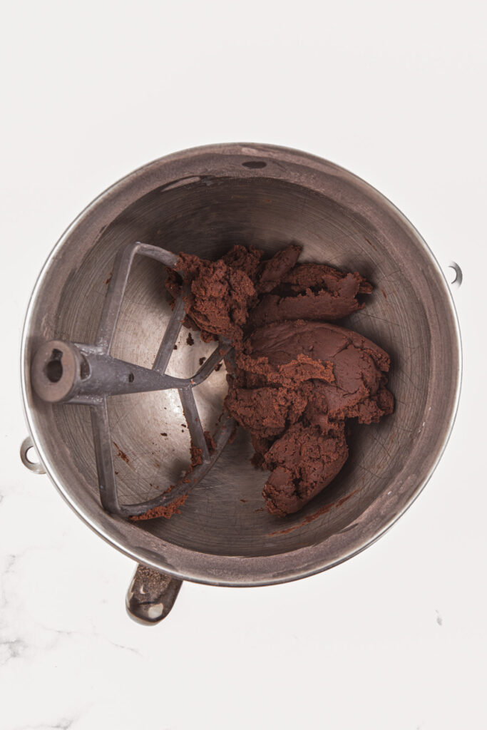 top down image showing a mixing bowl filled with chocolate dough and a paddle attachment