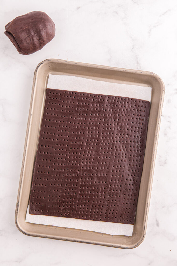 top down image showing a tray with chocolate dough rolled out and pricked with a fork