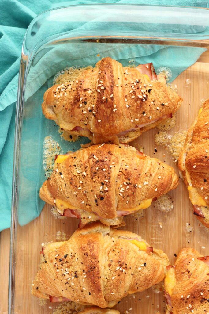 top down image showing toasted croissants in a glass dish that have seasoning on top and melted butter and cheese around the sides