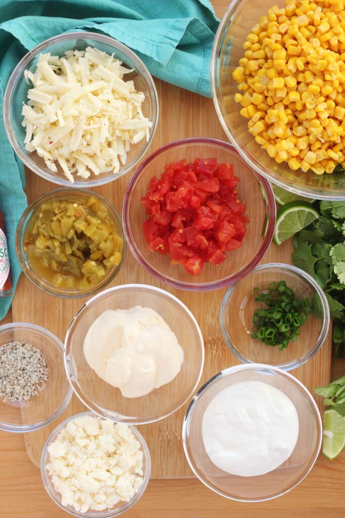 Top down image showing bowls each filled with an ingredient for a corn salad.