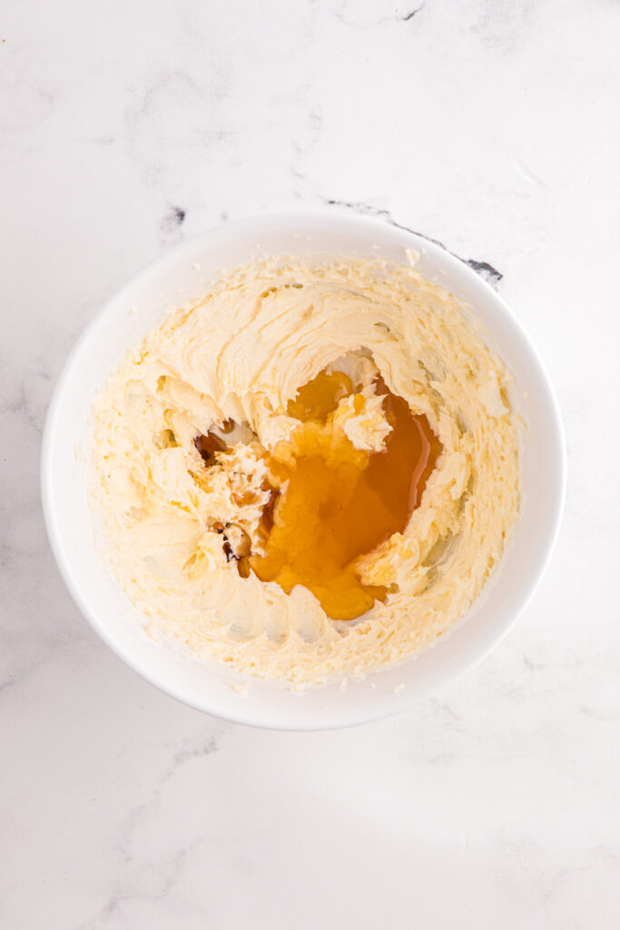 Top down image showing whipped butter in a white mixing bowl with a drizzle of hone
