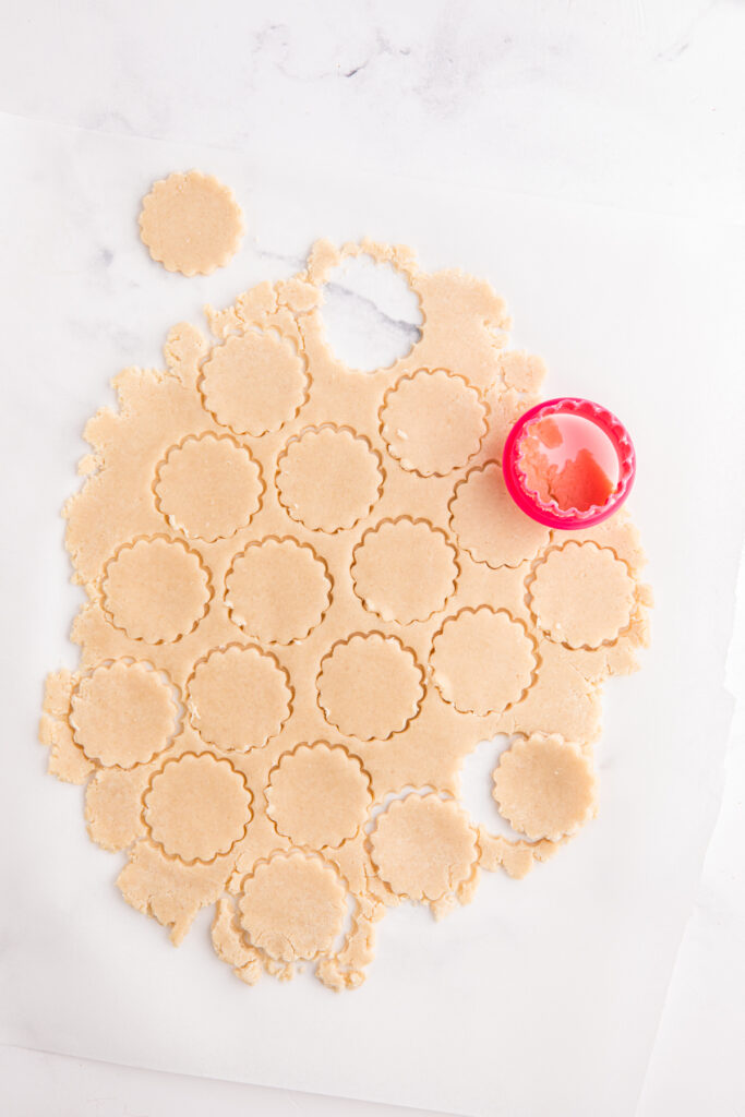 top down image showing cookie dough rolled out and cut with a round fluted edge cutter