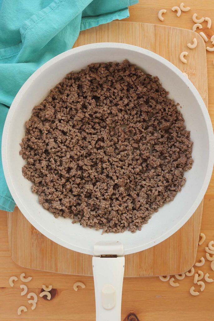 close up image showing a white skillet filled with cooked ground beef
