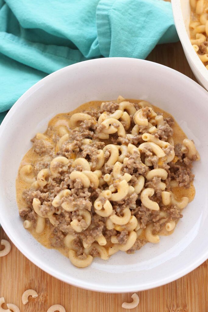 Top down image showing a bowl of macaroni noodle pasta with ground beef. 