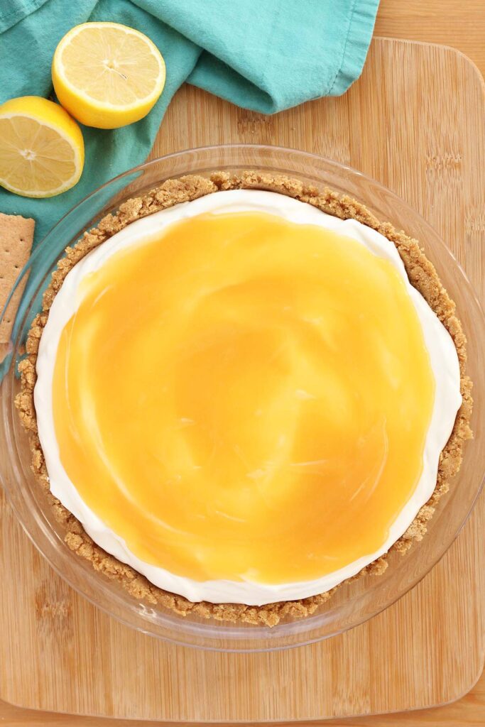 Top down image showing a pie crust filled with a white filling that has a layer of lemon curd on top