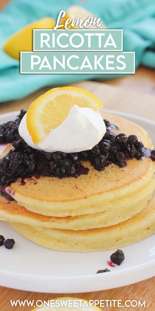 close up image showing a stack of 3 pancakes topped with lemon, blueberries, and whipped cream on a white round plate with a lifted lip. Text overlay reads "lemon ricotta pancakes"