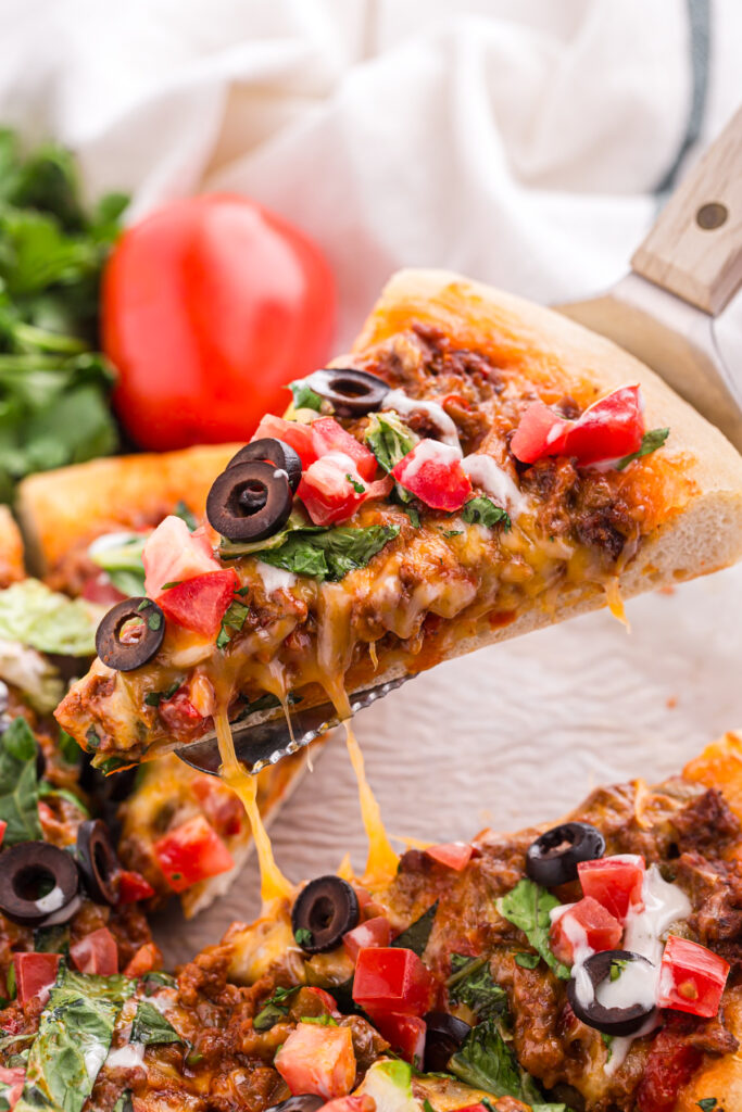 close up image showing a slice of pizza being pulled up with cheese melting around 