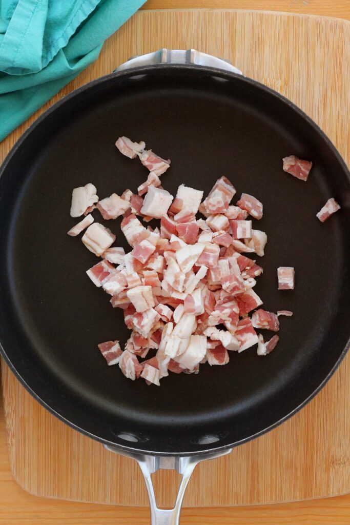 top down image showing a black skillet filled with uncooked bacon pieces