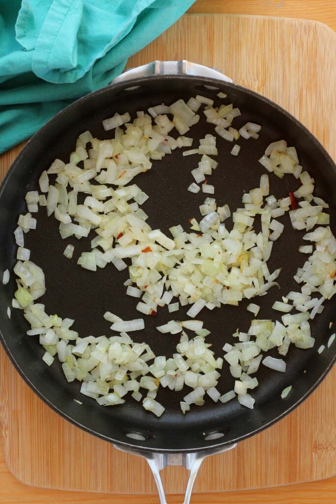 Top down image showing diced cooked onion inside a black skillet