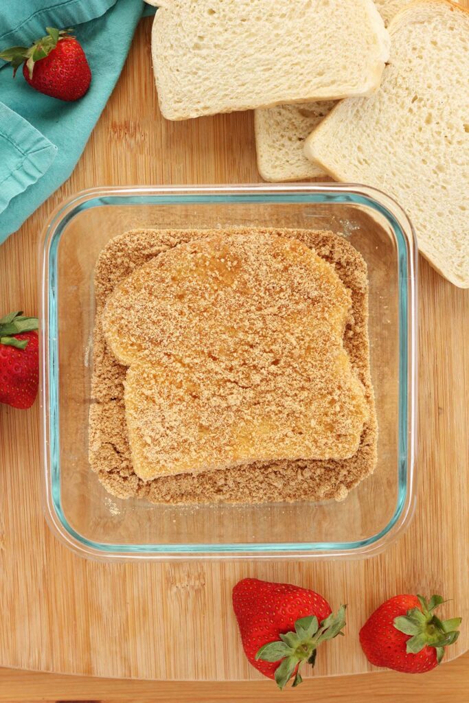 top down image showing a square glass dish filled with a bread slice covered in crumbs