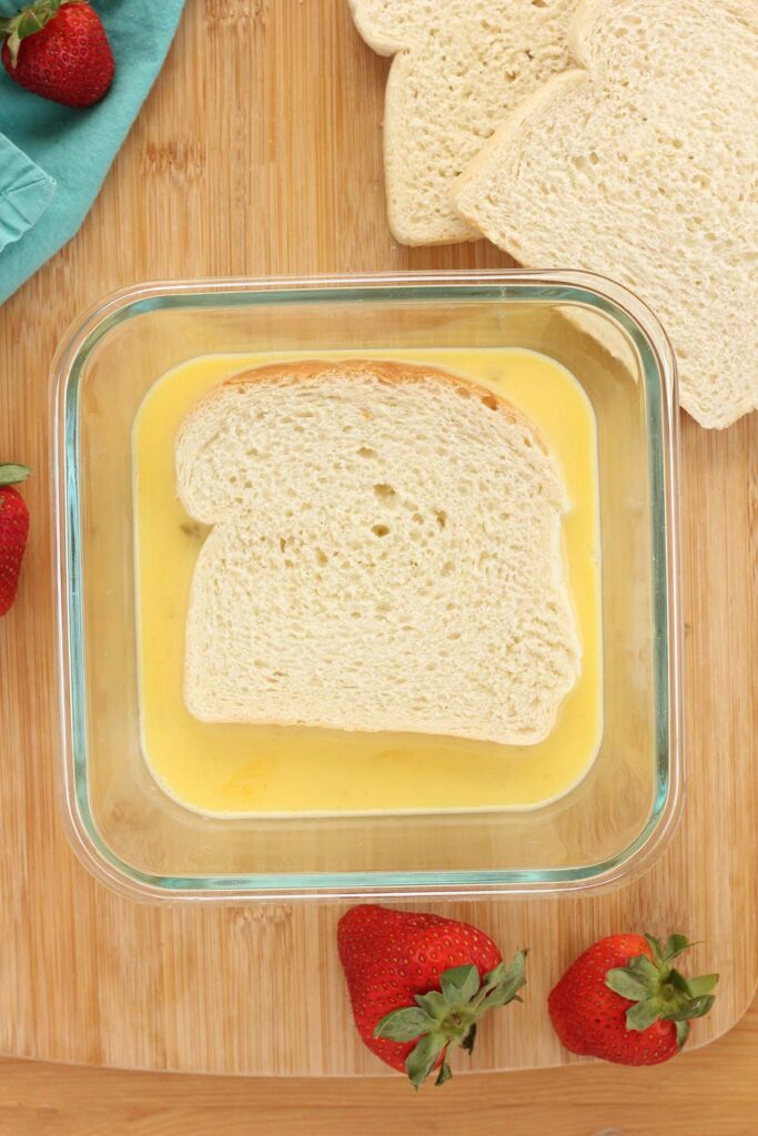 top down image showing a square glass dish filled with egg and a slice of bread