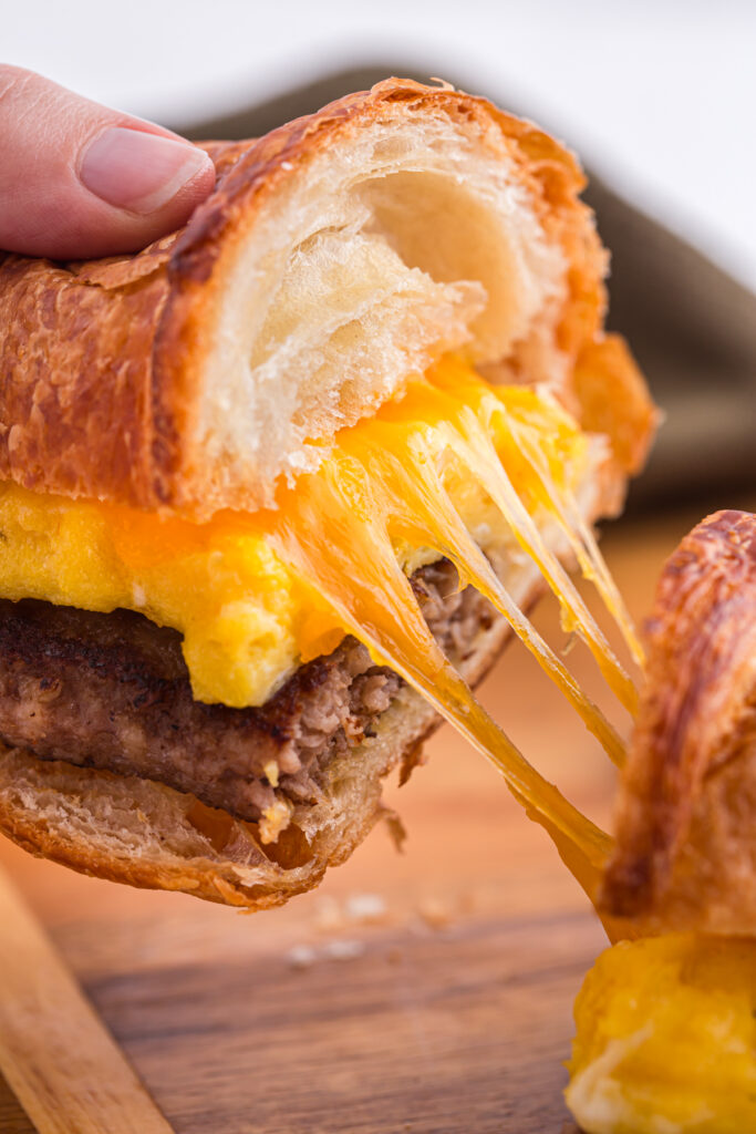 breakfast sandwich being pulled apart with cheese melted and stretching
