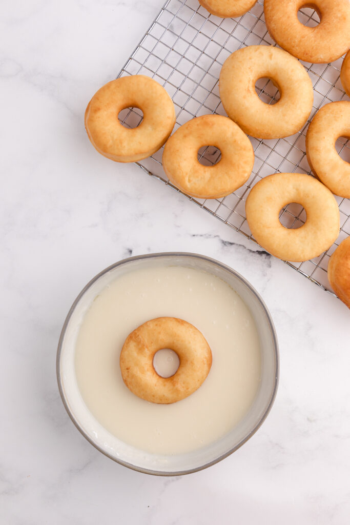 top down image showing a bowl filled with glaze and a single donut