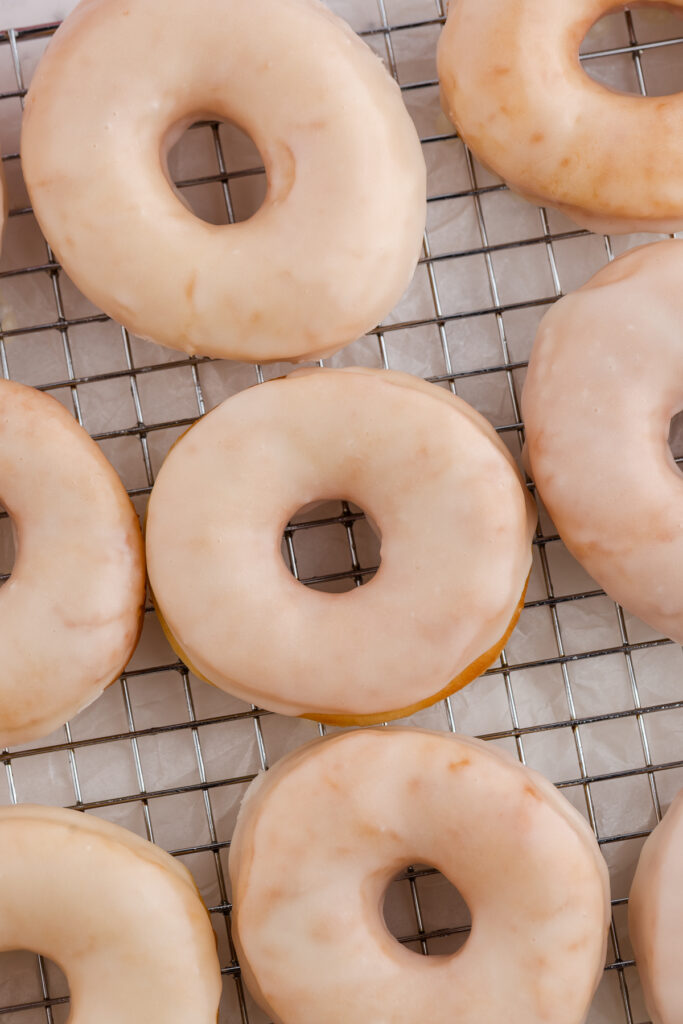 top down image showing glazed donuts on a wire rack