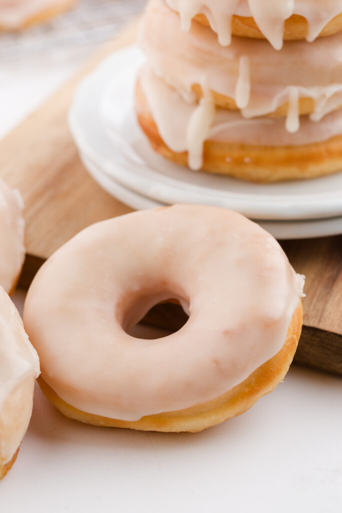 close up image showing a stack of glazed donuts sitting on a white table top