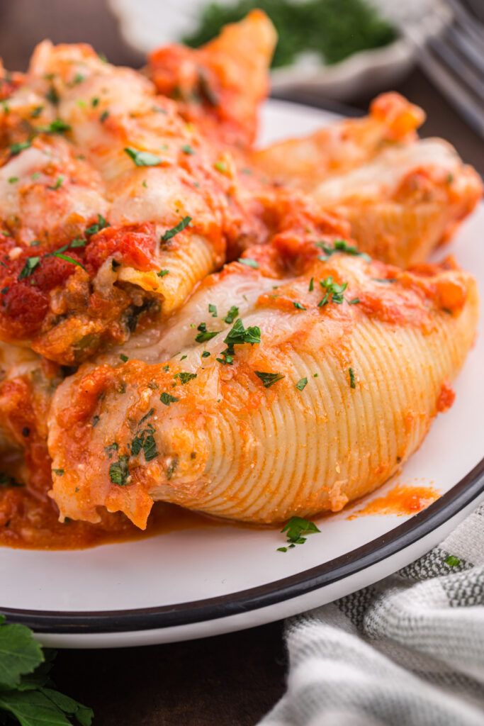 close up of a white plate with a black ridge topped with pasta shells 