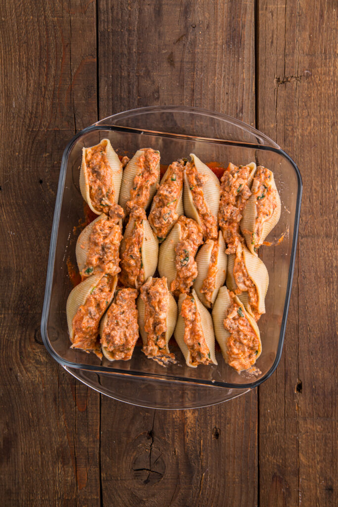 top down image showing a glass dish filled with pasta shells stuffed with a cheese mixture