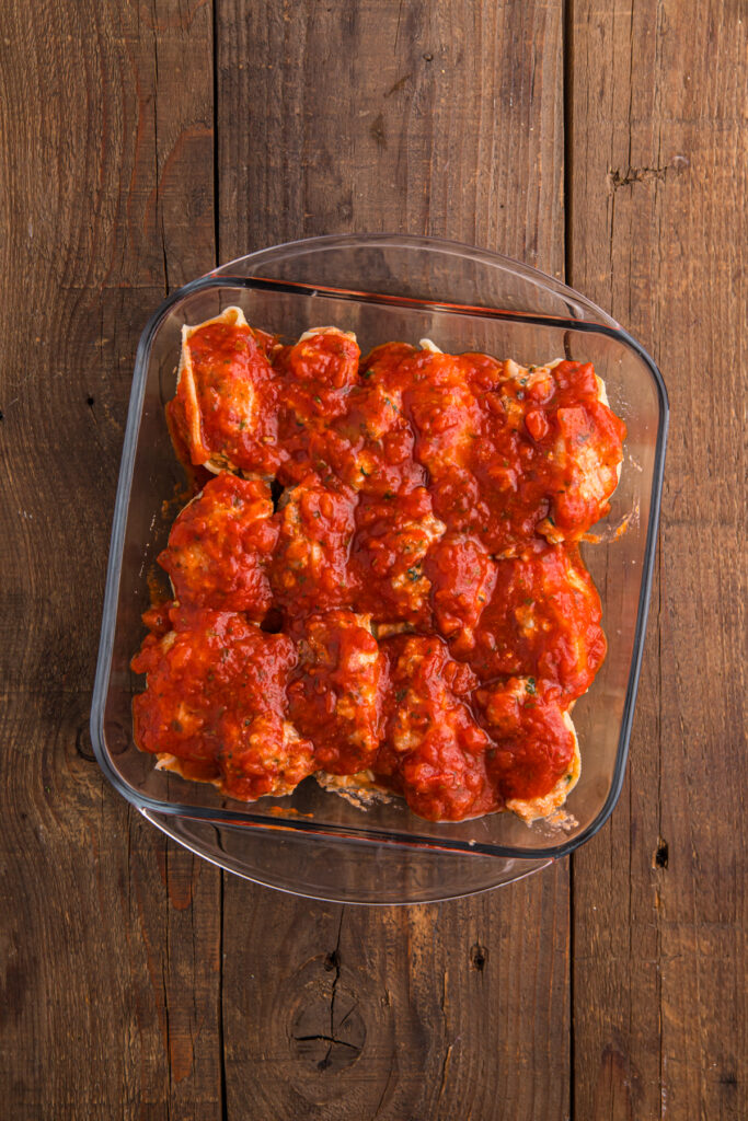 top down image showing a glass dish filled with pasta shells stuffed with a cheese mixture and topped with sauce