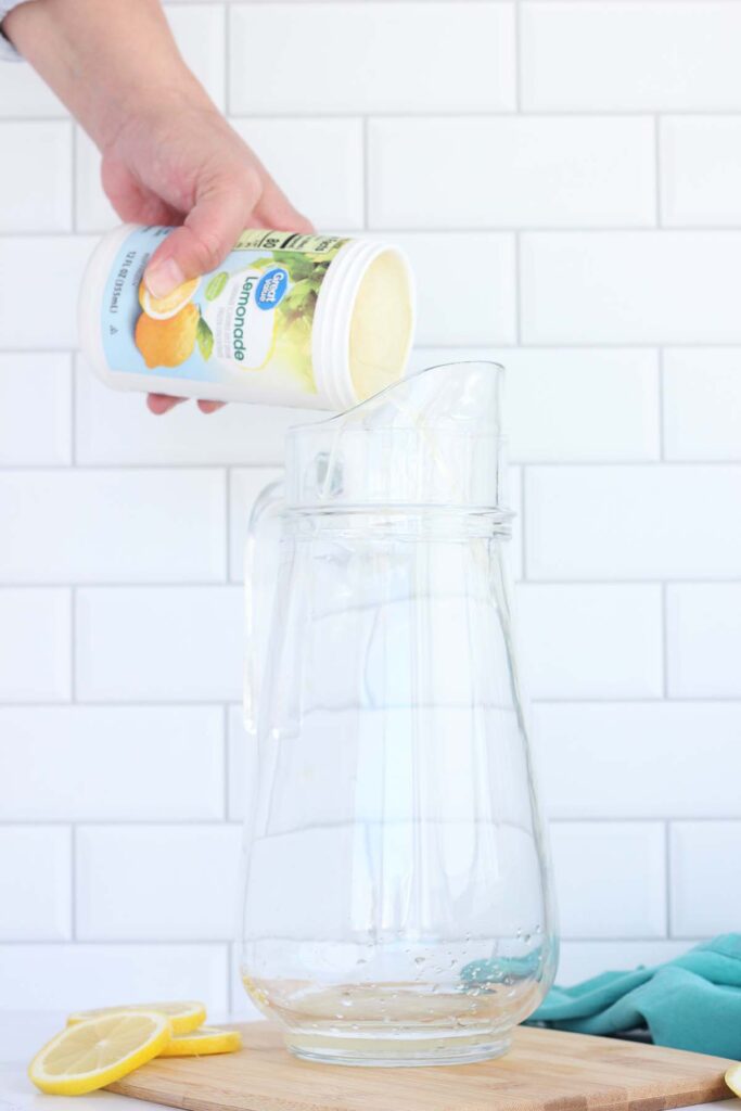 Lemonade concentrate being poured into a glass pitcher