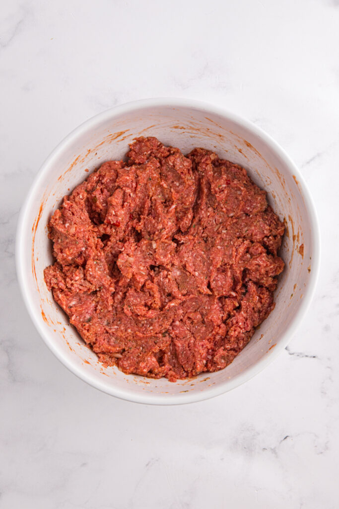 top down image showing a white mixing bowl filled with a ground beef mixture