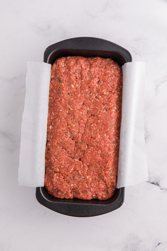 top down image showing a black loaf pan filled with a meat mixture