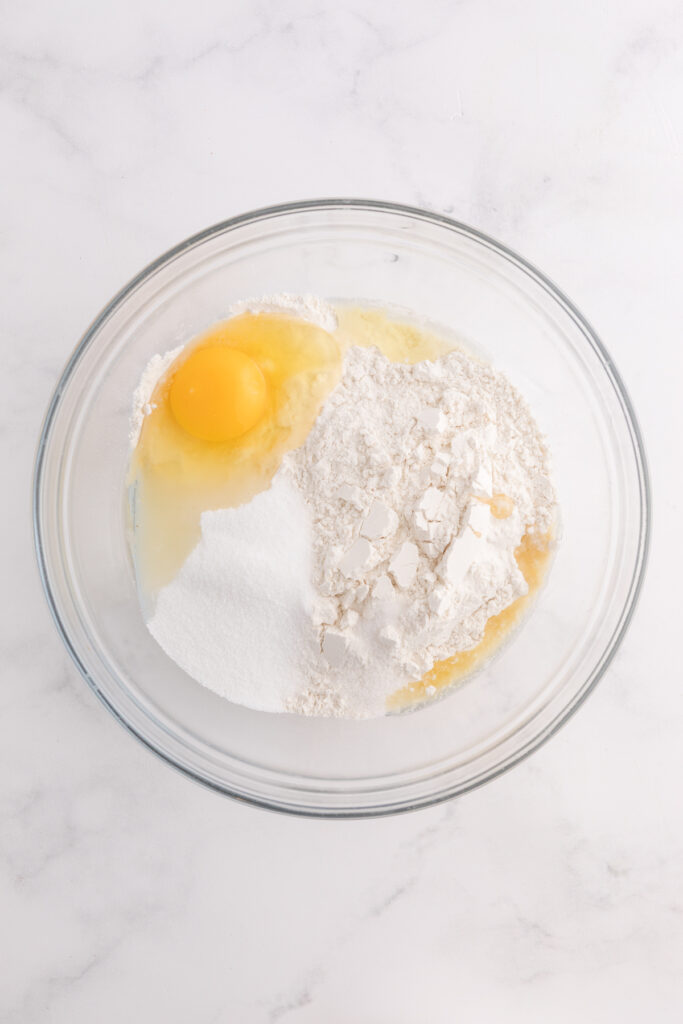 top down image showing a bowl with flour, sugar, and an egg