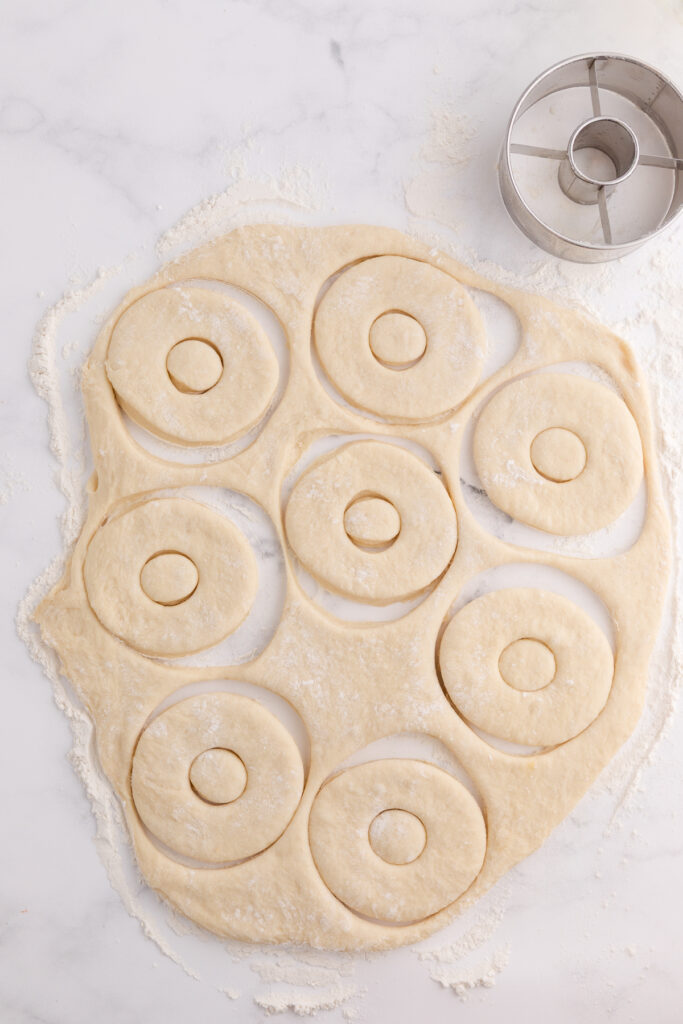 top down image showing dough rolled out and being cut by a donut cutter
