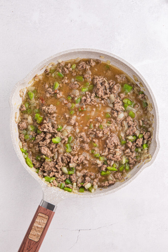top down image showing cooked ground beef with chopped onion and green pepper in a pan
