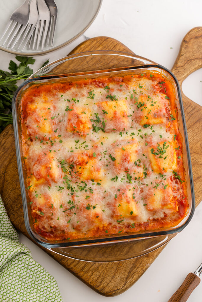 Top down image showing a glass square dish filled with pasta sauce and beef with shredded cheese that has been melted over the top
