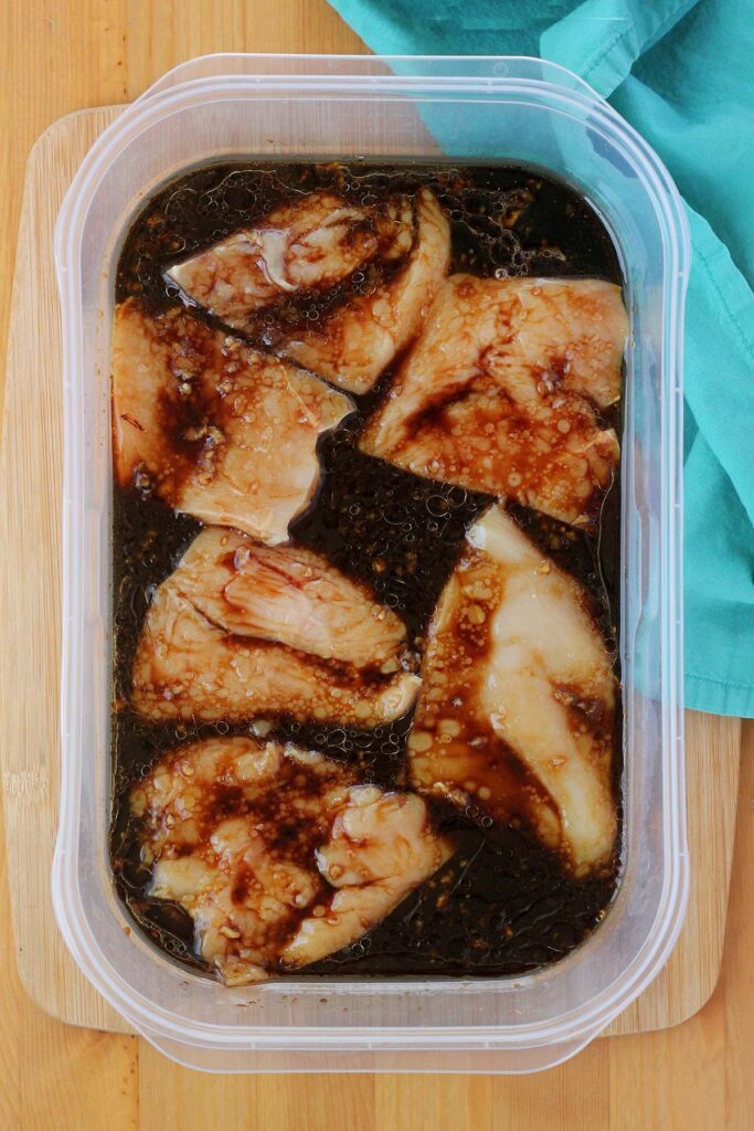 top down image showing a plastic dish filled with marinade and chicken pieces