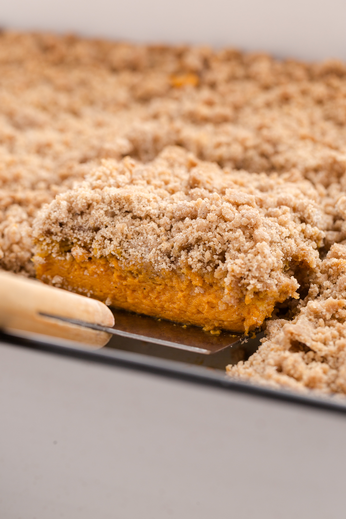 a type of pumpkin pie with crumb topping being pulled from a baking dish