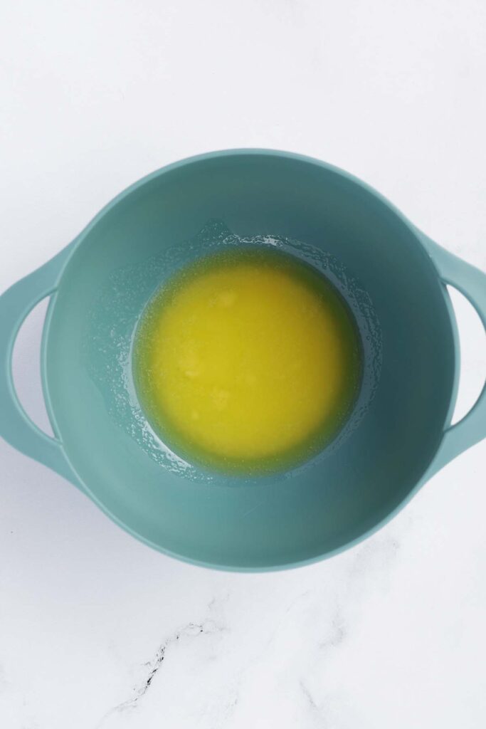 Top down image showing a blue mixing bowl filled with melted butter