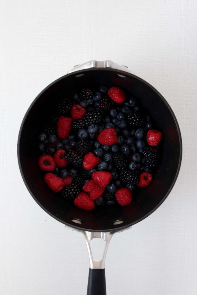 top down image showing berries in a black pot on a white table
