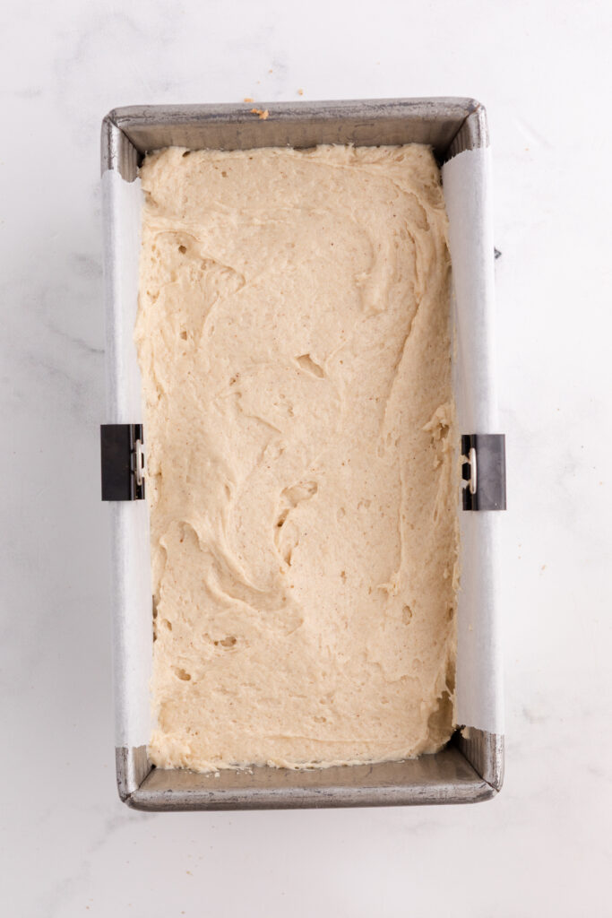 Top down image showing a loaf pan that has a parchment paper and batter