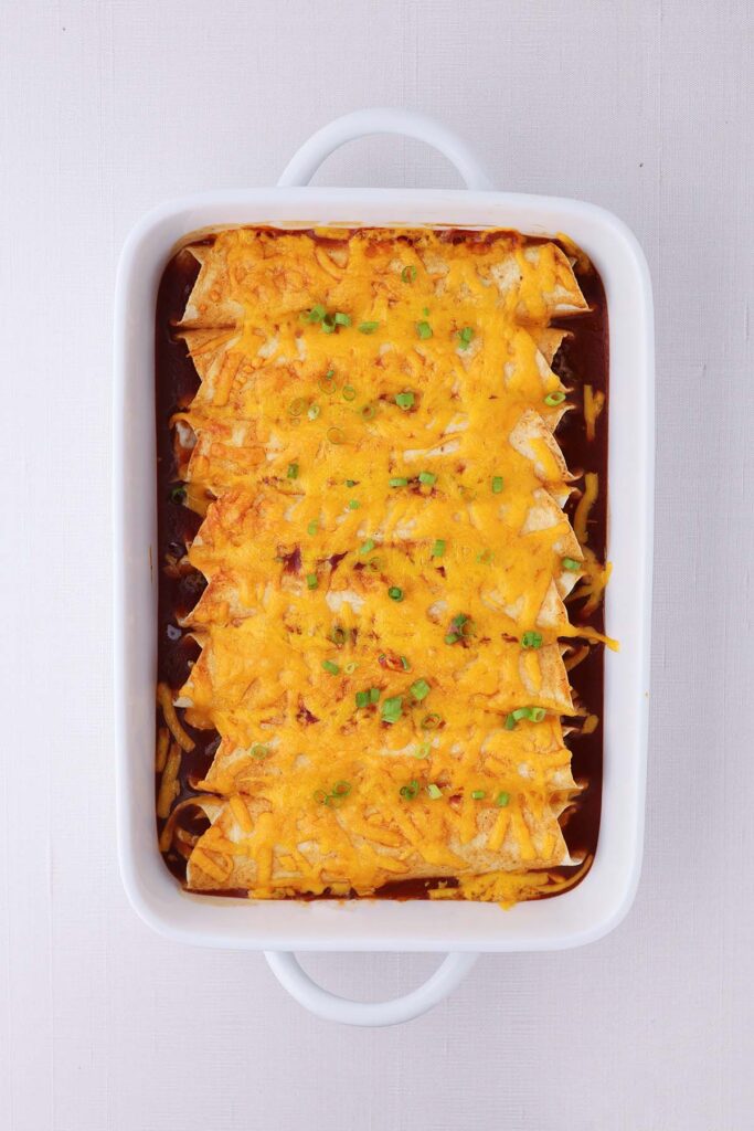 top down image showing a white baking dish filled with enchiladas that have been baked