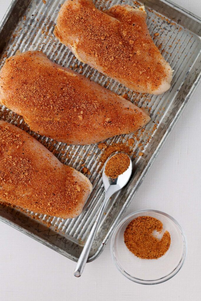 close up image showing chicken breast spreinkled with seasonings