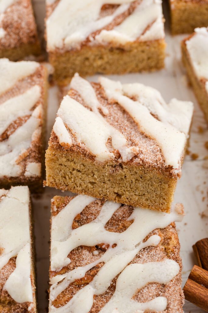 close up image showing squares of blondies with a cinnamon topping and icing drizzle