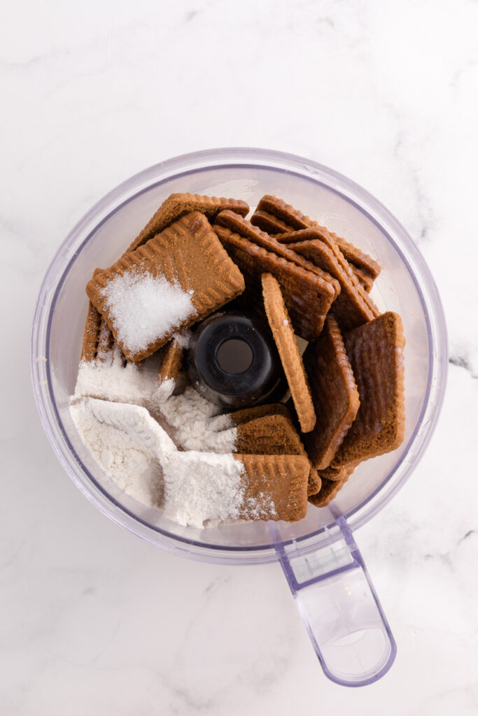 Top down image showing a food processor filled with uncrushed cookies and flour
